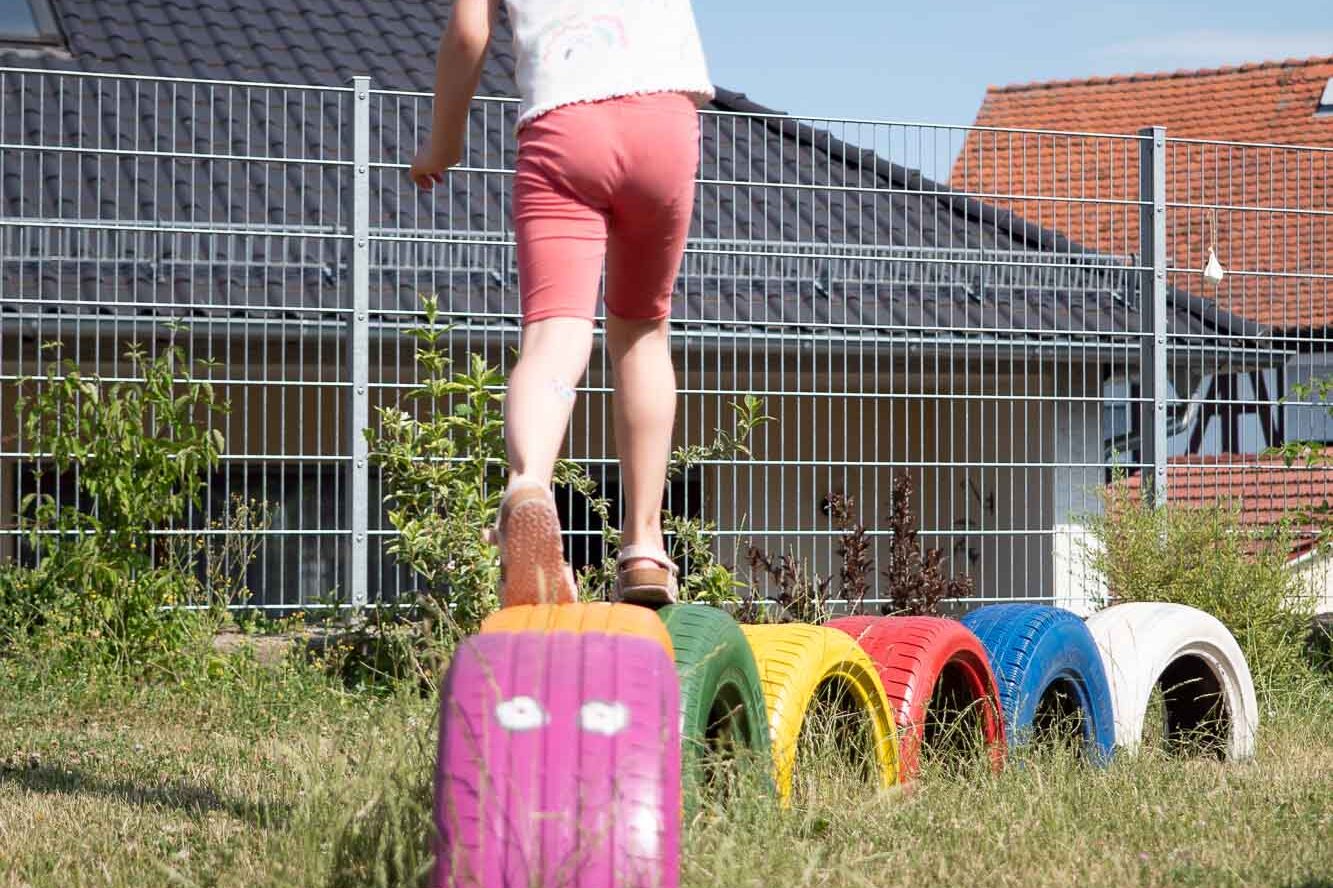Kind balanciert über bunt bemalte Reifen